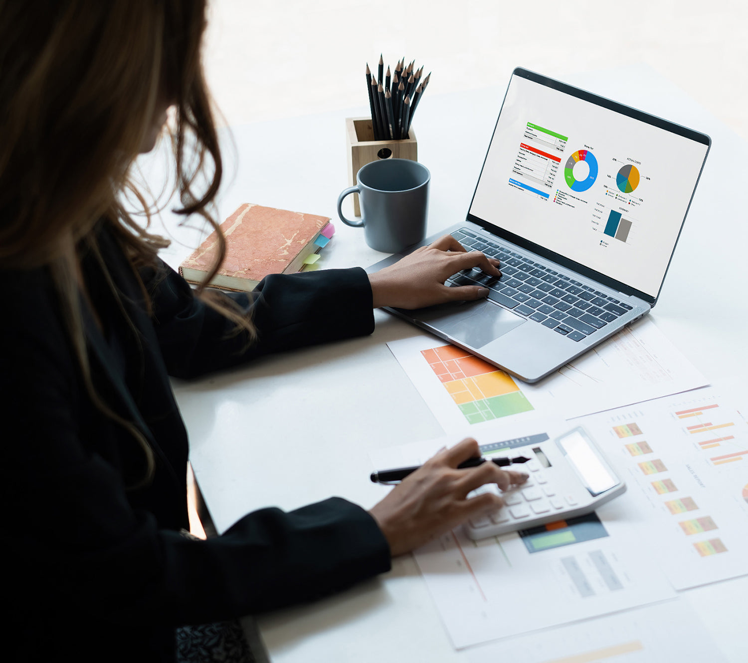 Business woman assessing statistics on laptop and papers